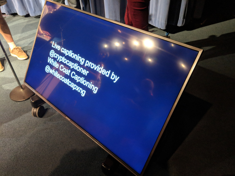 TV screen used to show live captions during the talks. Current text: Live captioning provided by @cryptocaptioner White Coat Captioning @whitecoatcapxng