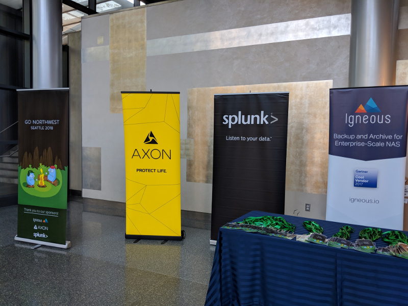 Signs at the registration table for Go Northwest.  From left to right: Go Northwest conference sign, Axon sponsor sign, Splunk sponsor sign, and Igneous sponsor sign.